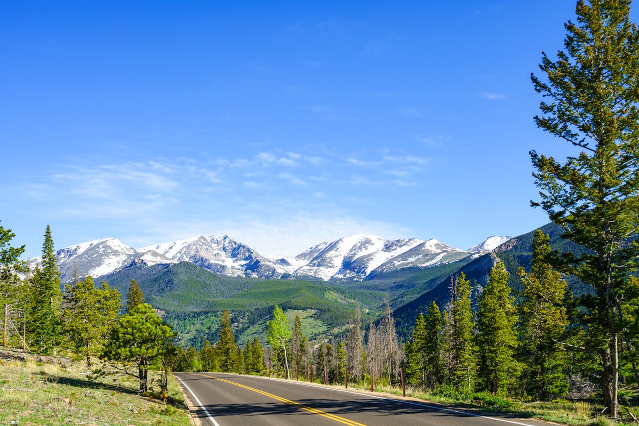 Explore the stunning views of snow-capped Rocky Mountains from a winding road in Estes Park, Colorado.